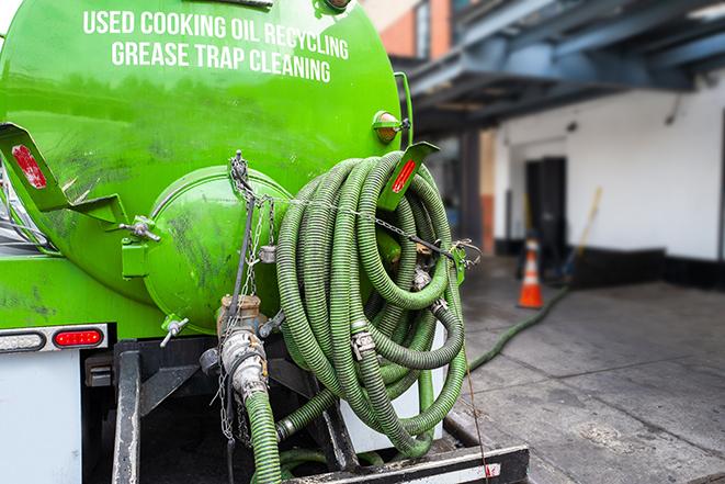 a grease trap being pumped by a sanitation technician in Newport Coast